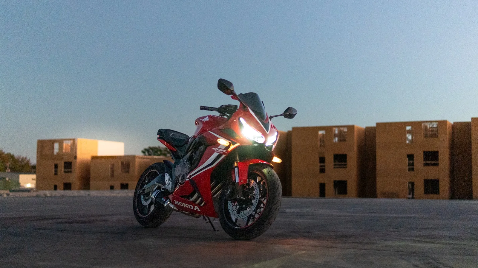 Rode Honda CBR sportmotor met koplampen aan bij schemering, foto door David Leonard op Unsplash